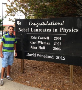 Carlos Hernández-García junto a una placa distintiva con los premios Nobel en Física logrados en la Universidad de Colorado.