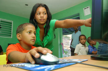 Una facilitadora de El Naranjal muestra a una niña cómo operar la computadora en la sala digital inaugurada aquí por el Indotel.