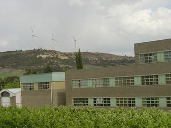Edificio de la ETSIA con molinos productores de energía eólica al fondo.