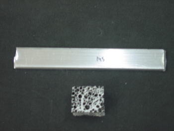 Arriba una barra de aluminio compacto, abajo espuma de aluminio donde se aprecia la porosidad