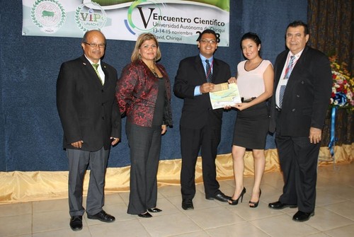 Entrega de reconocimiento por parte de la vicerrectoría de investigación y posgrado al licenciado Elmer Benjamín Camarena, en compañía de la doctoranda Enith González (izquierda).