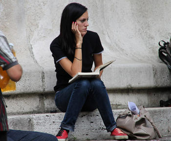 Joven sentada en la calle con un libro. Foto: UNED.