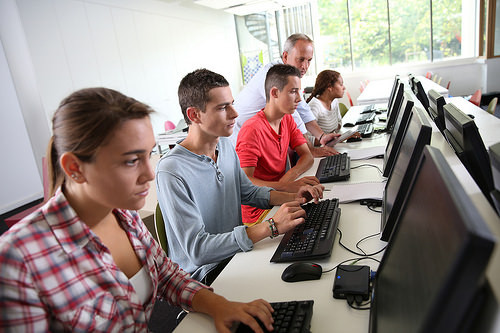 Varios estudiantes en un aula de ordenadores.