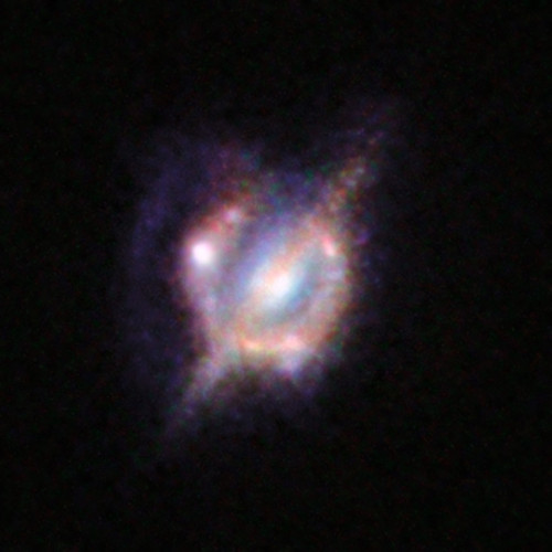 Fusión de galaxias en el universo distante amplificada a través de una lente gravitacional. Crédito: ESO/NASA/ESA/W. M. Keck Observatory