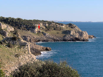  Grotta del Cavallo (flecha roja) se abre en la bahía de Uluzzo; localizada en el parque regional natural de Portoselvaggio (Apulia; sur de Italia)./ Annamaria Ronchitelli.