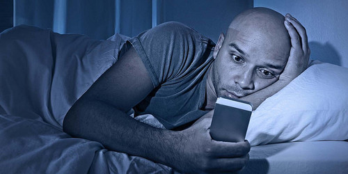 Un hombre consulta el móvil en la cama. Foto: Bosland Corp.