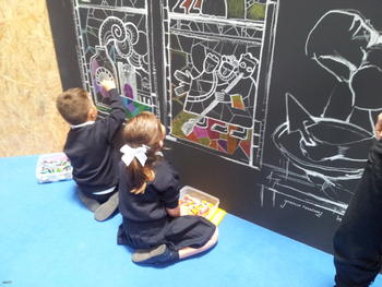 Dos niños pintan sobre pizarra unas vidrieras de la catedral de León.