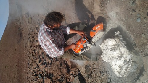 Uno de los investigadores emplea maquinaria cortadora de roca para extraer los fósiles del megarraptor.