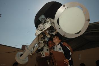 Un escolar observa el espacio desde un telescopio.