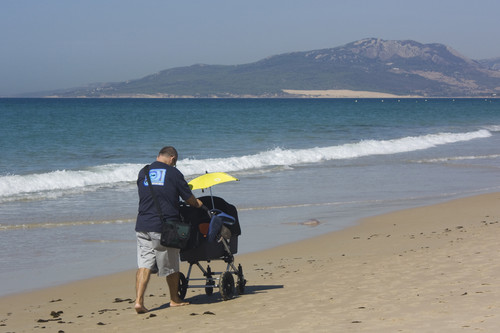 Un padre pasea por la playa con su bebé. / Antonio Guerra.