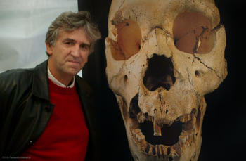 Arsuaga junto a una imagen que reproduce el Cráneo 5 encontrado en Atapuerca.