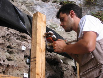 Ángel Carrancho recoge una muestra con una brújula magnética en el yacimiento de El Mirón. 