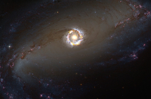 Imagen compuesta de la galaxia espiral barrada NGC 1097. Las observaciones de ALMA están en rojo (HCO+) y verde/naranjo (HCN) superpuestas en una imagen óptica captada con el telescopio espacial Hubble. FOTO: ALMA (NRAO/ESO/NAOJ)